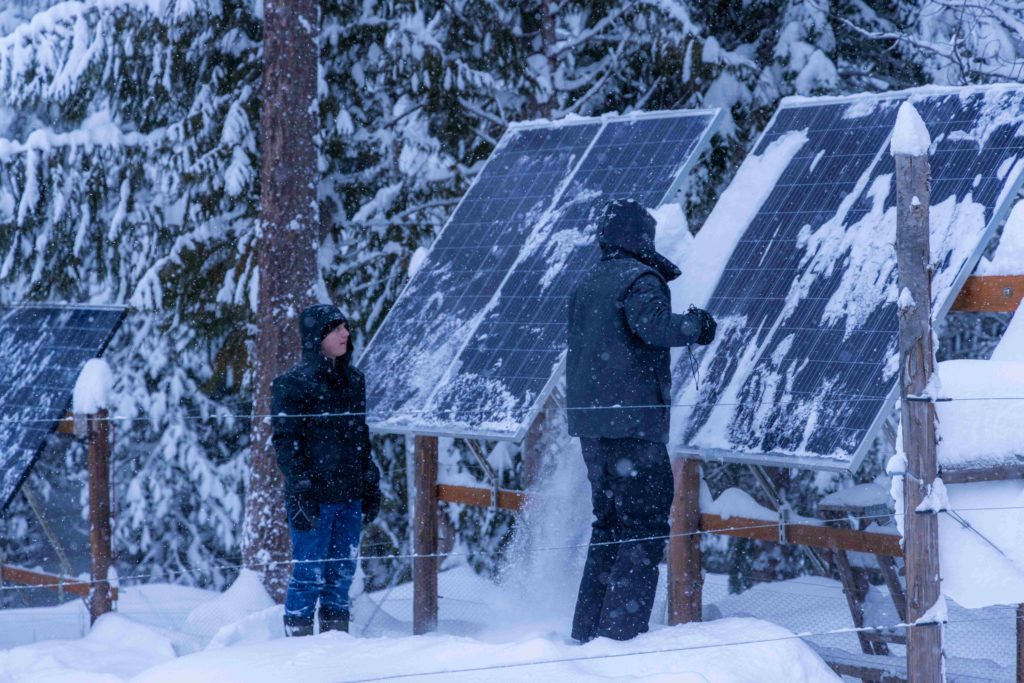 men wiping off solar panels in snow