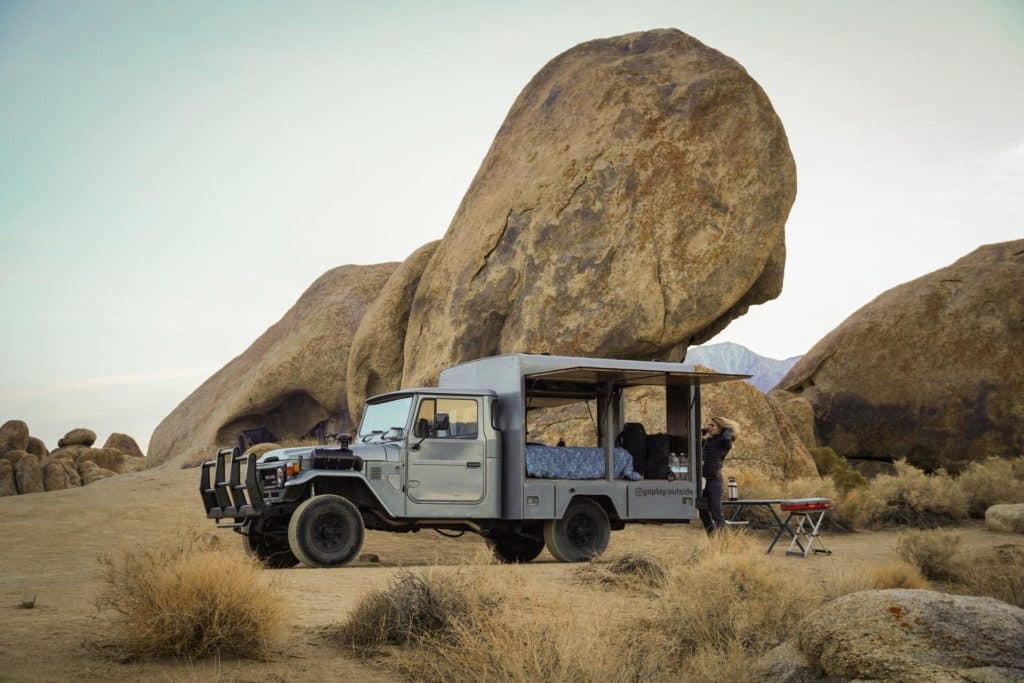 Overlanding vehicle parked in front of a large rock