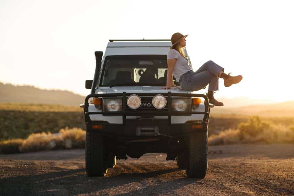 woman sitting on the front of her toyota landcruiser overlanding vehicle