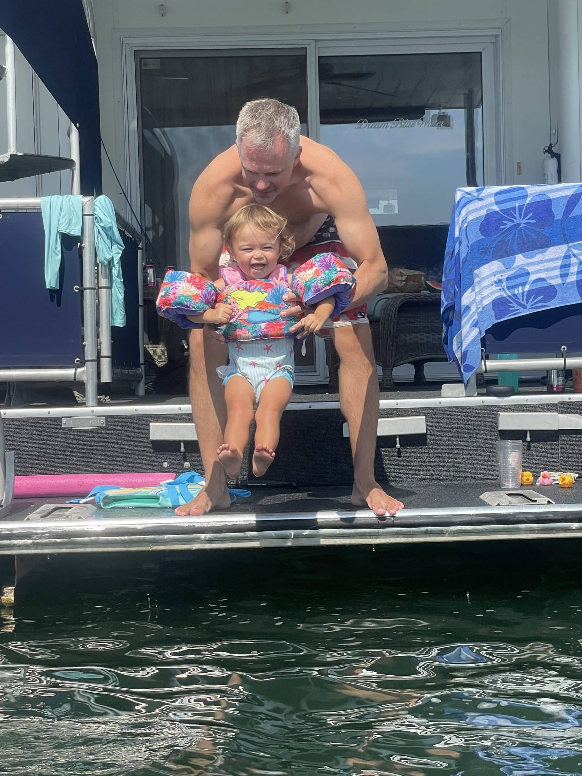 Trey putting Clare in the water off the back of their houseboat