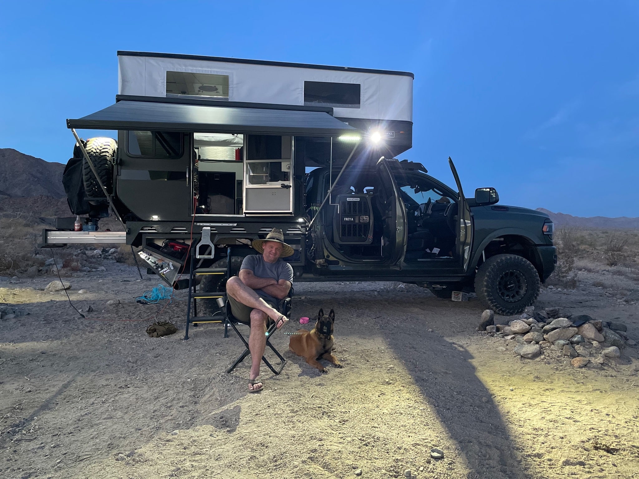 Sean Silvera sitting in a camping chair next to his German Shepard, Freya, in front of his overlanding rig