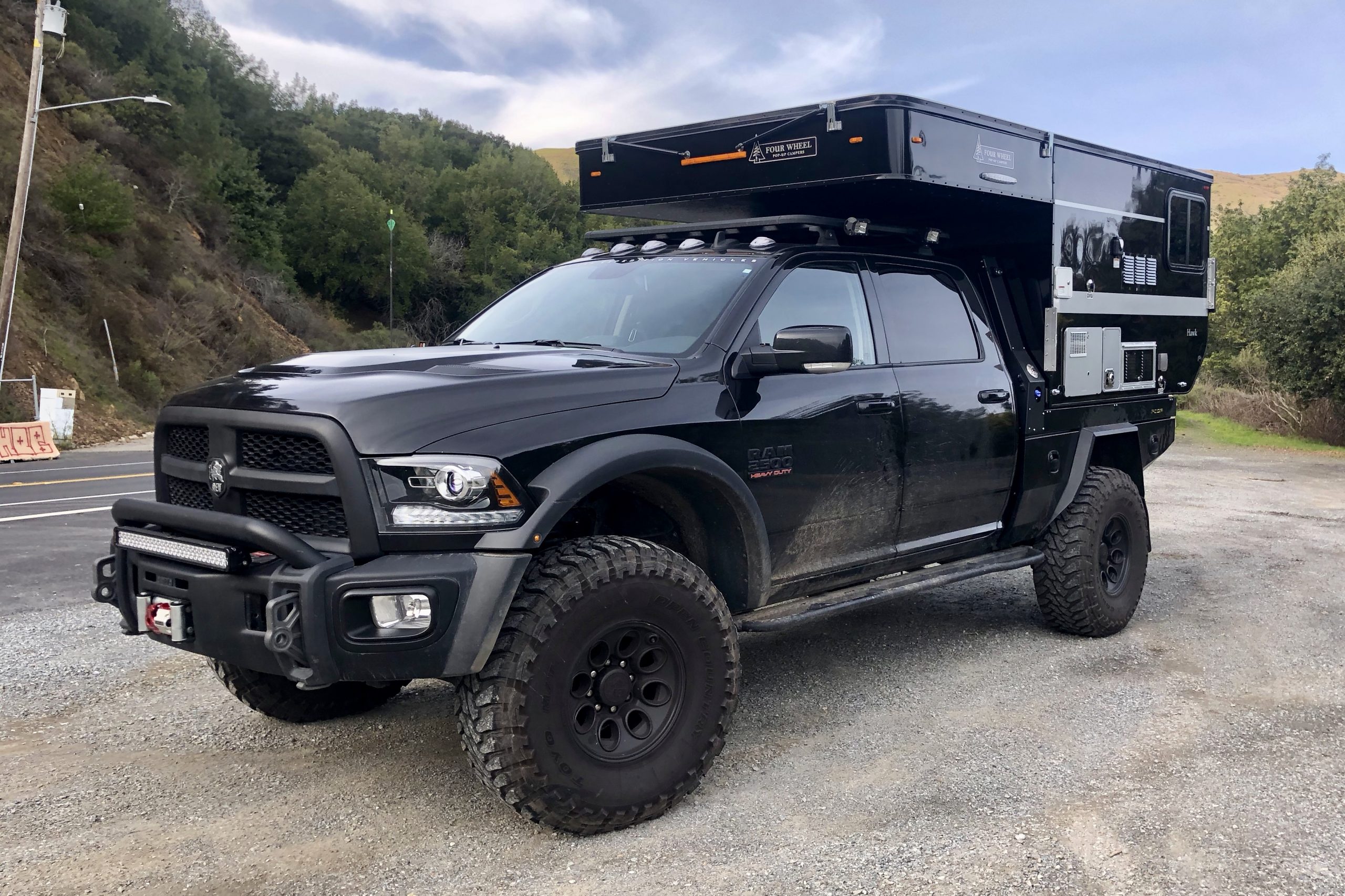 Sean Silvera's Black Dodge Ram Truck with a truck camper folded down in the truck bed