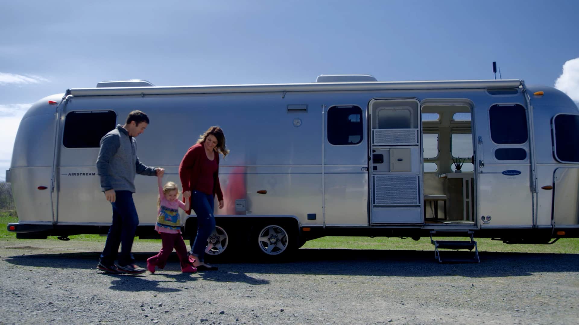 Less Junk More Journey holding hands with their child outside of their Airstream