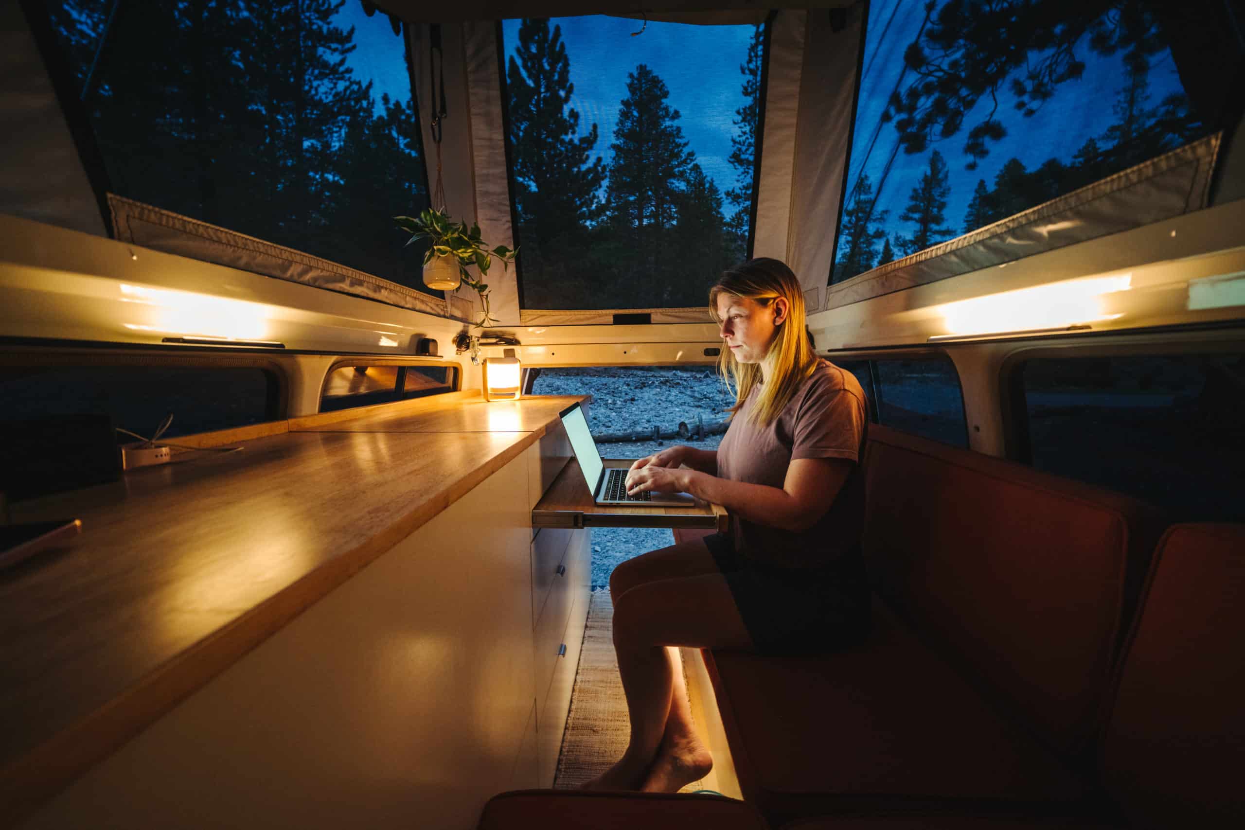 woman working on her laptop inside of a pop-up camper