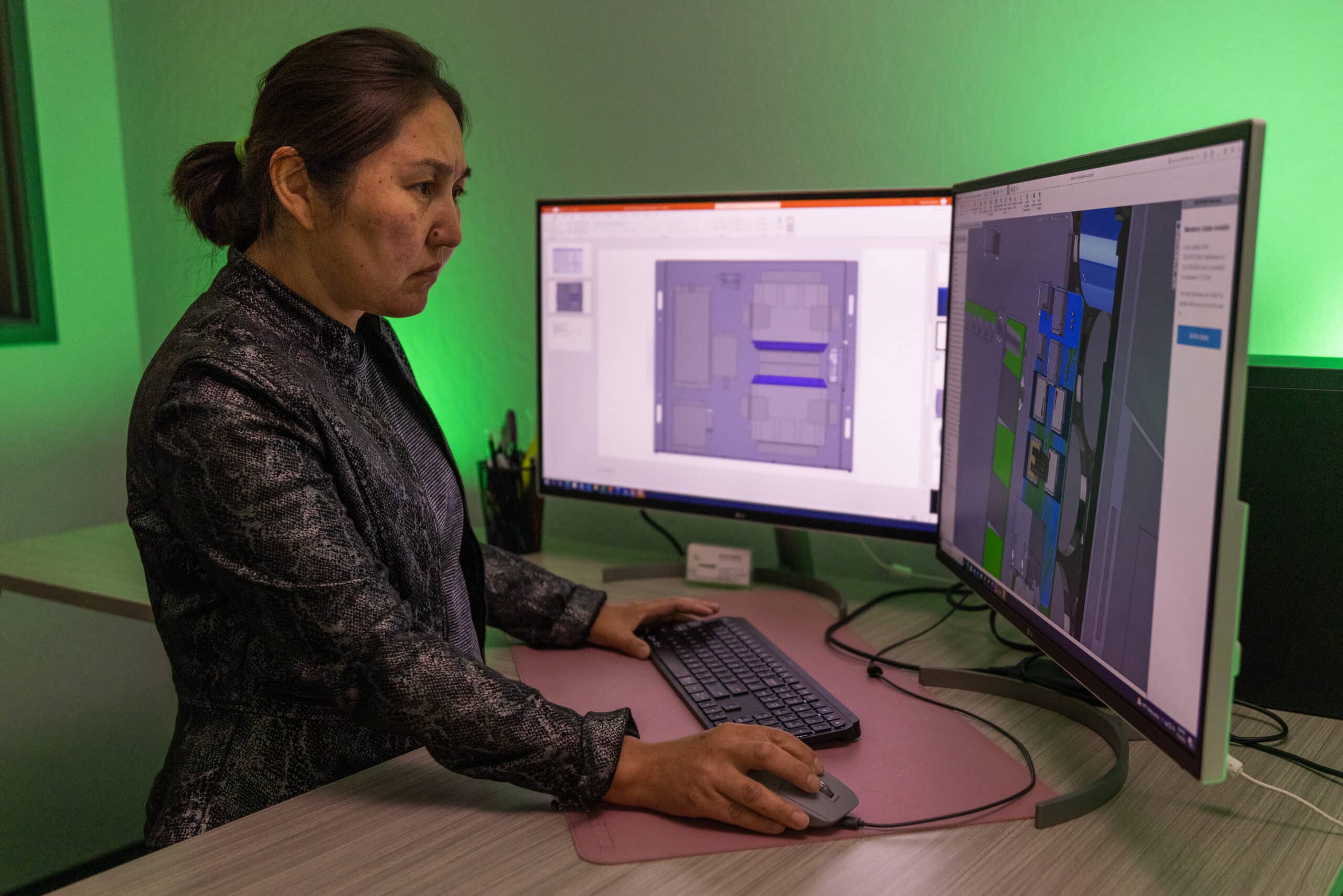 woman standing at a desk working on 2 computer monitors