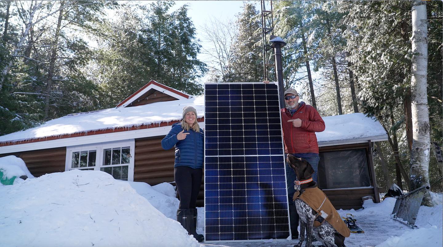 Peter Van Stralen and his wife pointing at a large solar panel