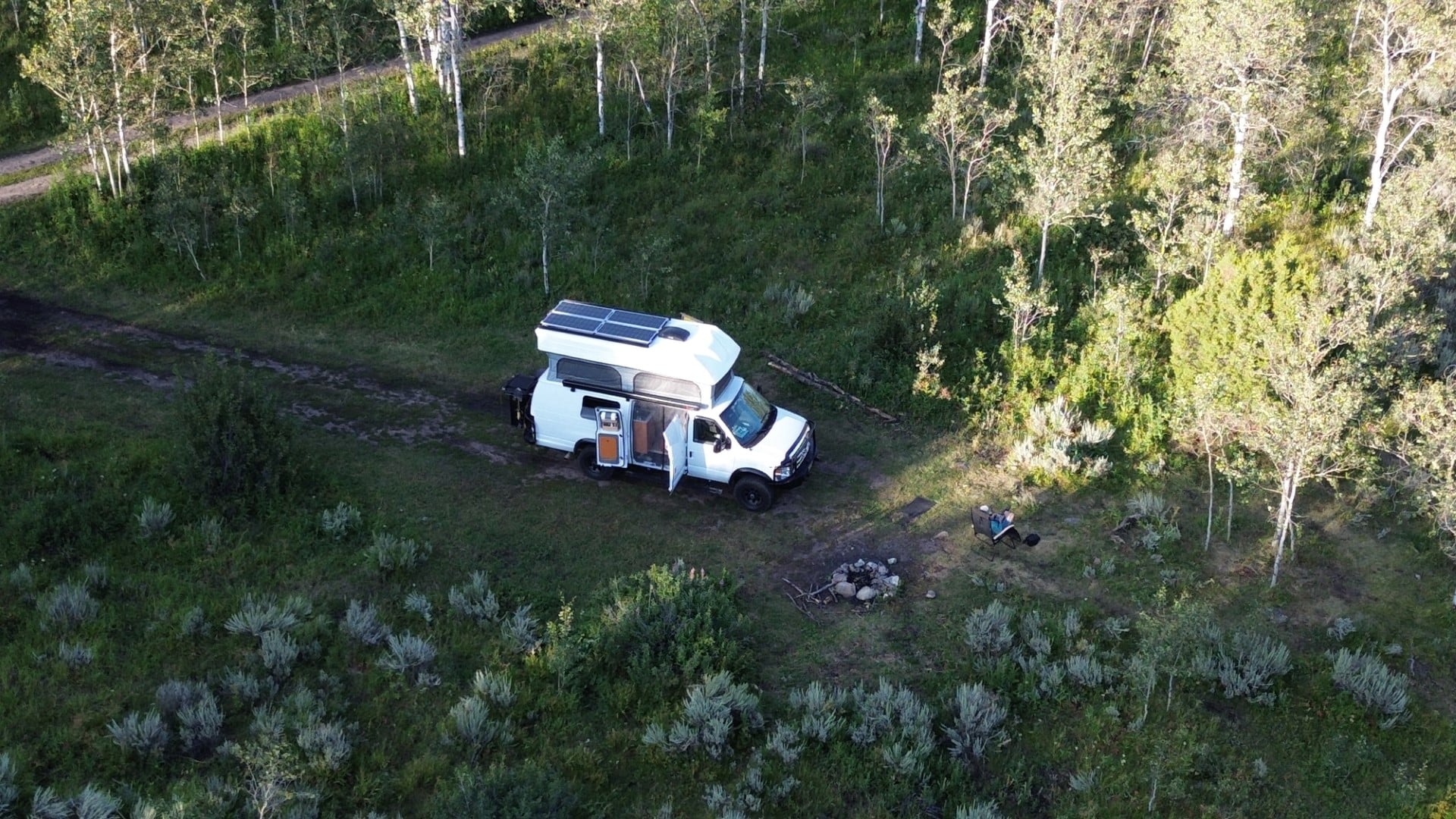 A drone shot of a white van boondocking off-grid.